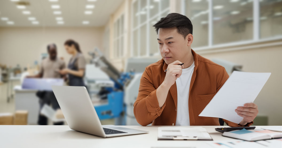 Print owner reviewing web to print software on a laptop in a print warehouse